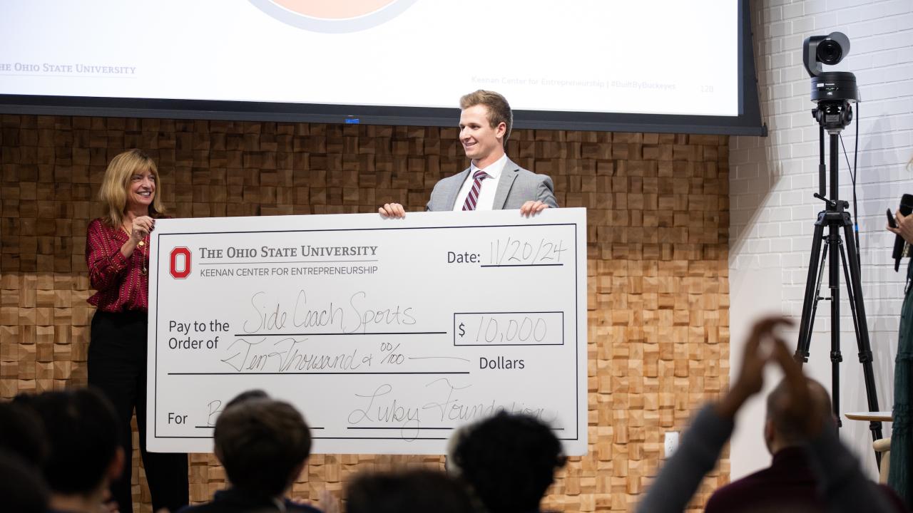 BOSS winner Luke Carrell with prize check on stage